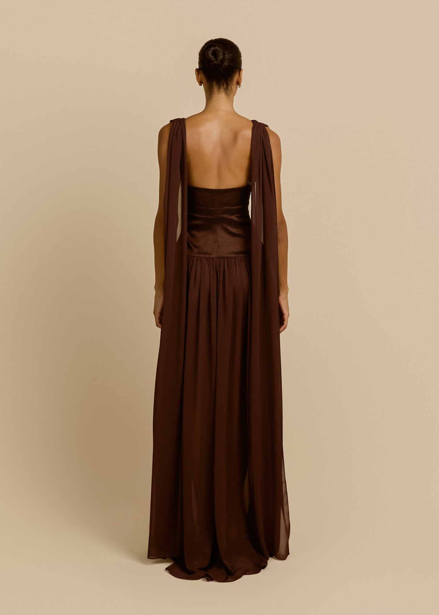 Woman wearing a brown dress with a matching shawl on a beige background