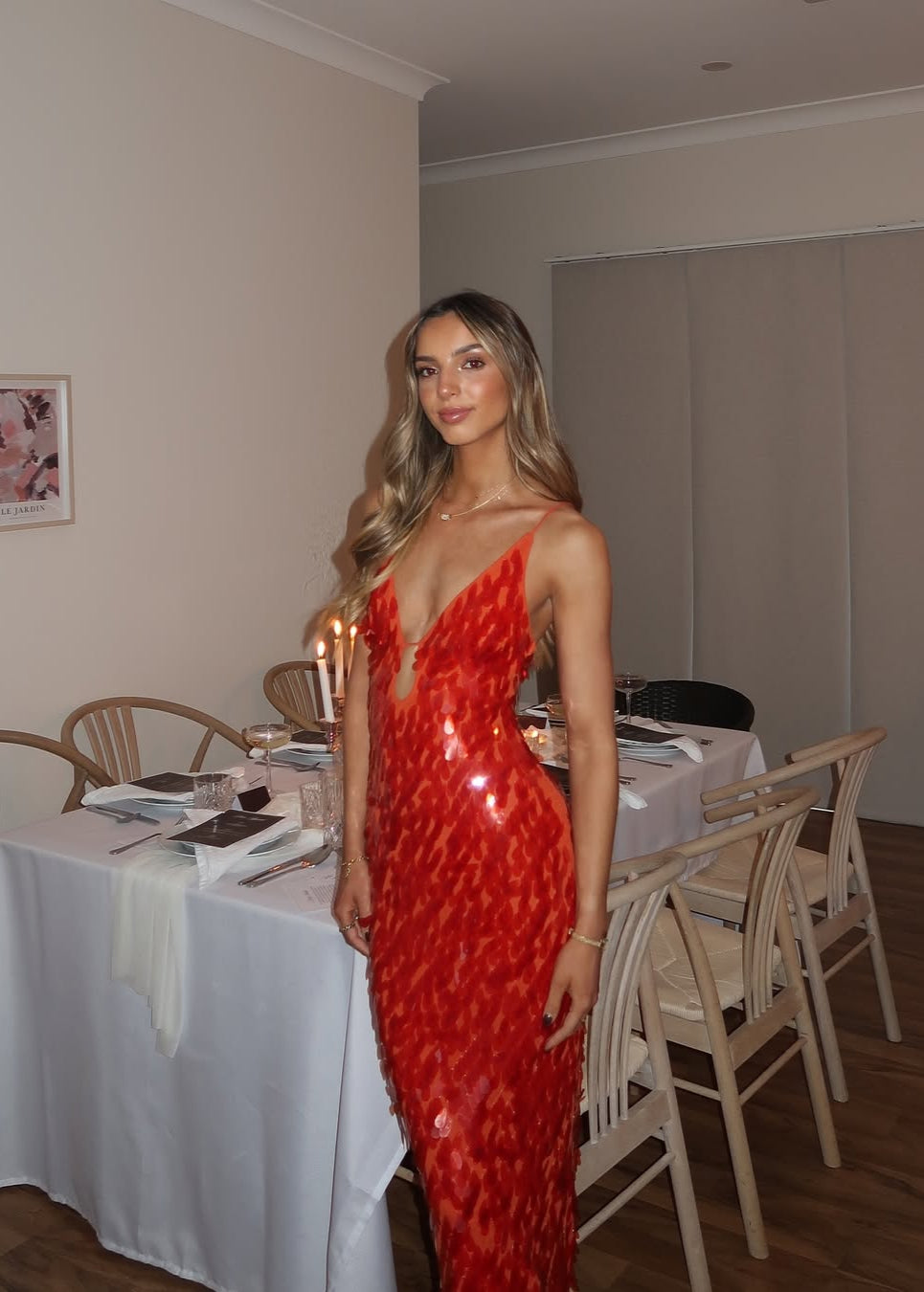 Woman in a red dress standing in a dining room with tables and chairs.