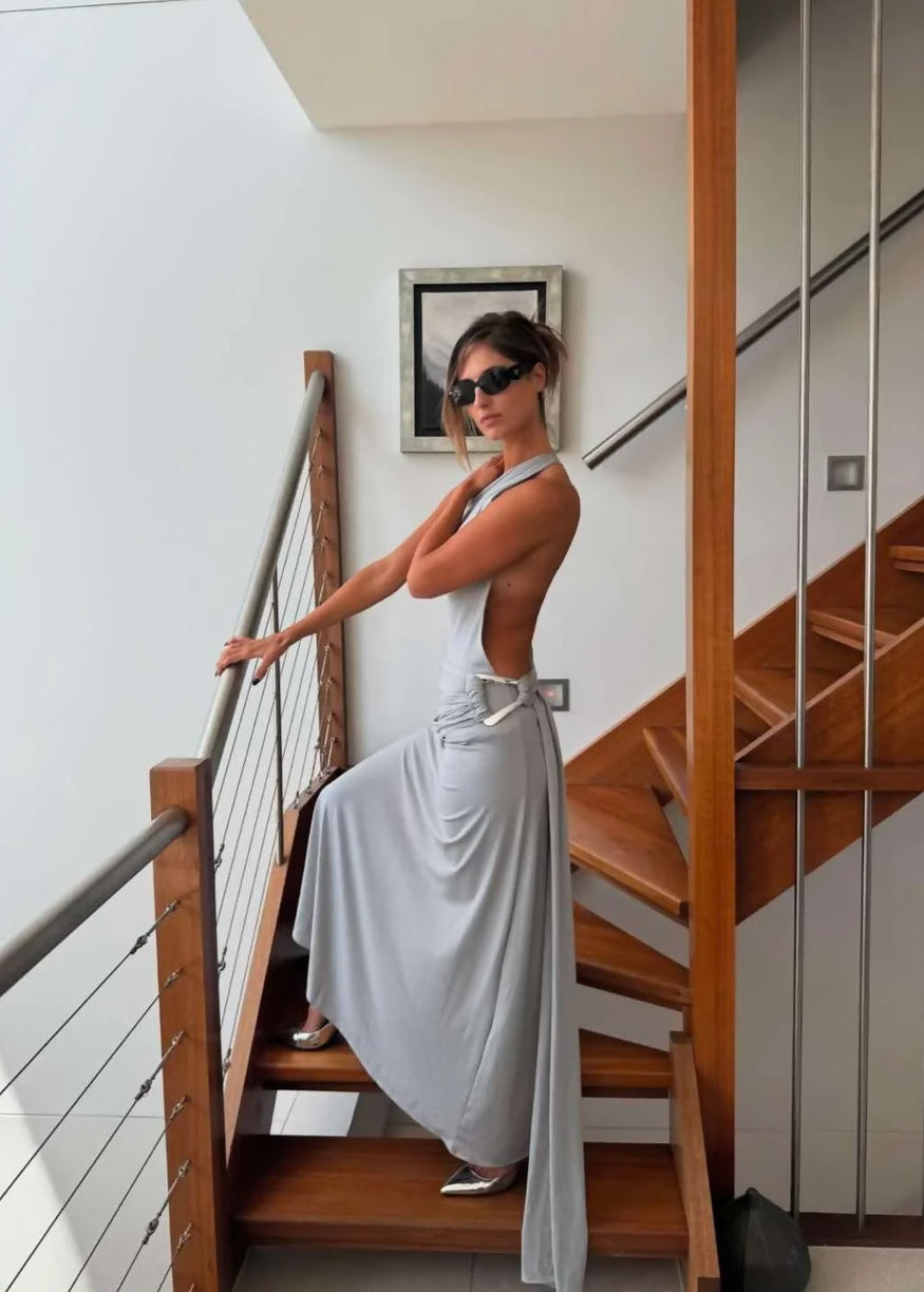 Woman in a white dress standing on a wooden staircase with a neutral background