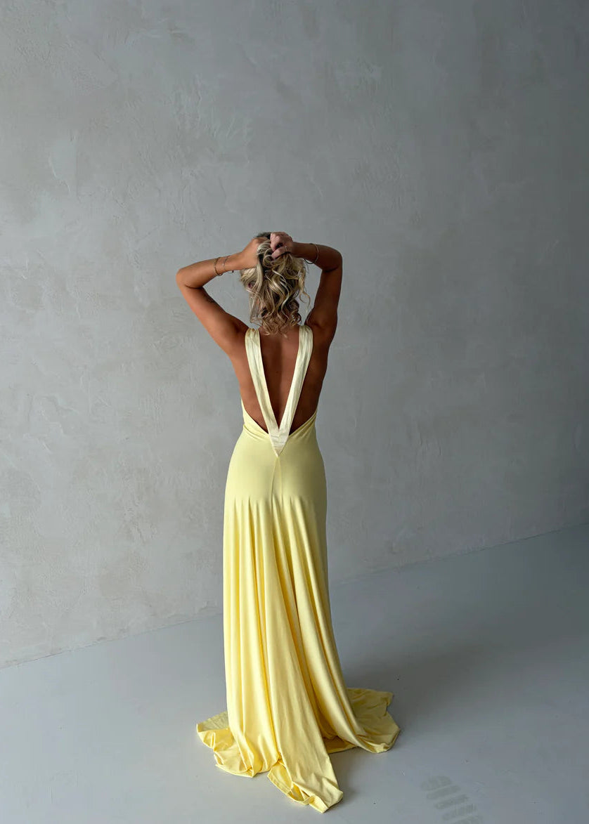 Woman wearing a yellow evening gown against a plain background