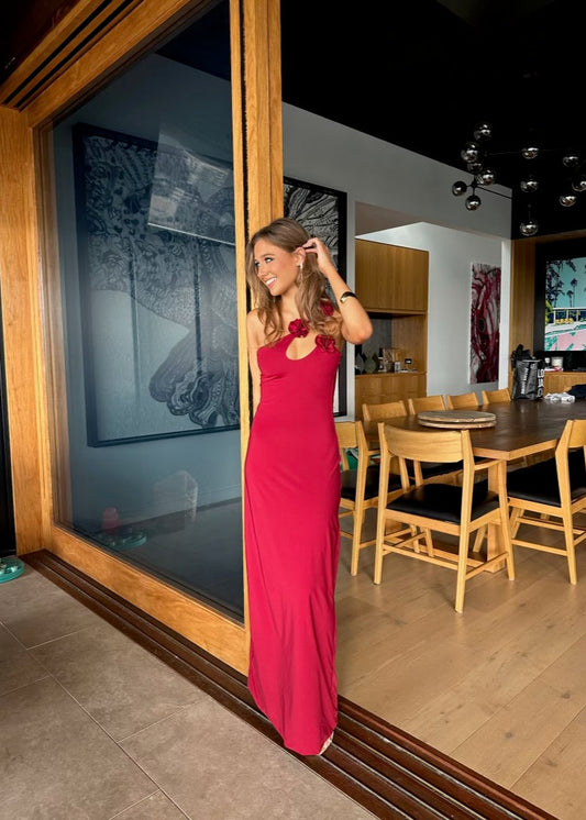 Woman in a red dress standing in front of a large mirror in a modern interior setting.