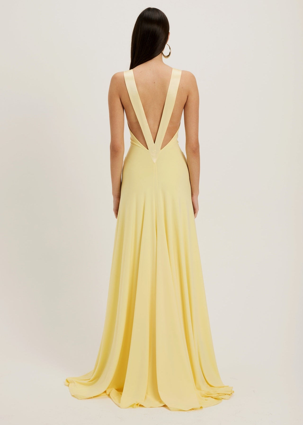 Woman wearing a yellow evening gown with a plunging neckline on a plain background