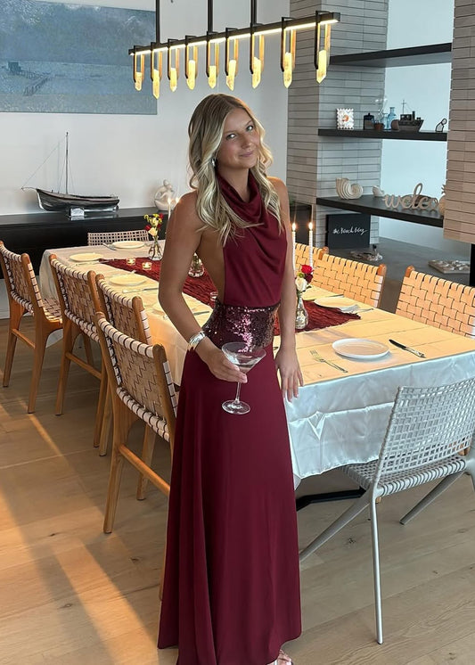 Woman in a red dress holding a glass of wine in a modern dining area.