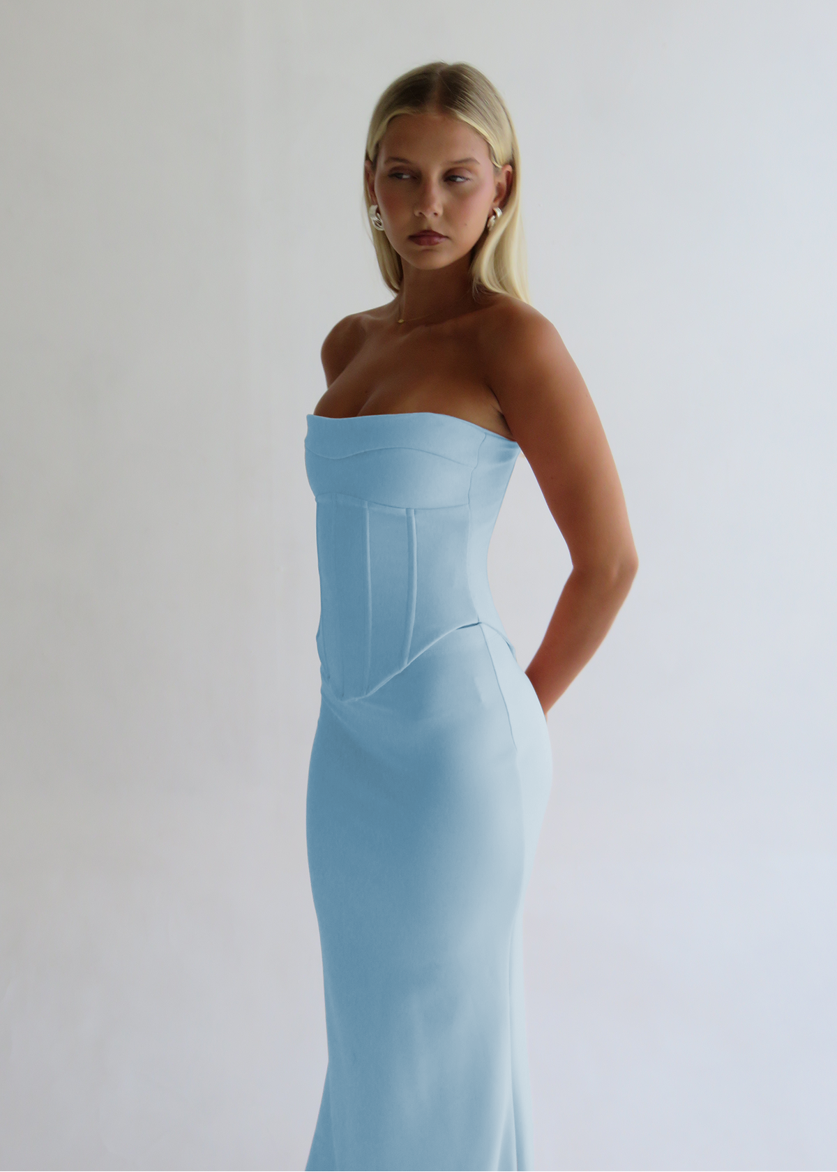 Woman wearing a light blue strapless dress against a white background