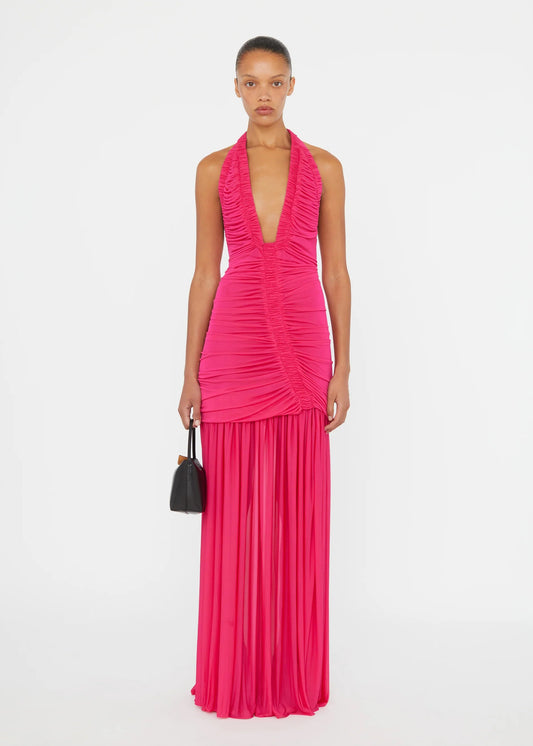 Woman wearing a bright pink halter neck gown on a white background