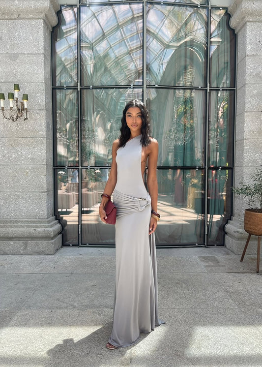 Woman in a silver dress standing in front of a large glass door with a chandelier above.